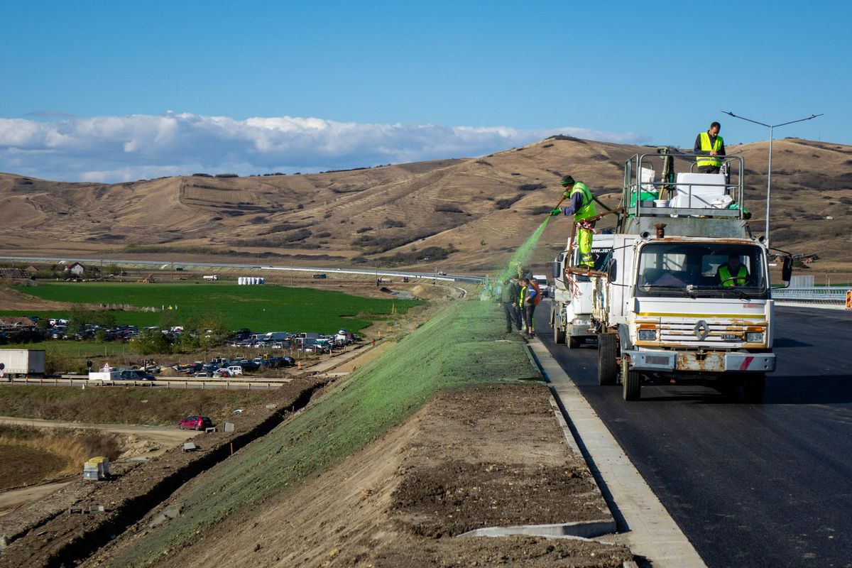 Example of a crew hydroseeding a roadside slope with green mulch from a truck